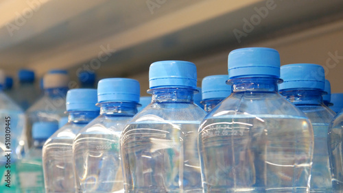 Close-up of many blue plastic bottles with drinking water on a store shelf