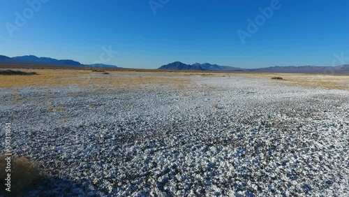 Going across white sand desert with small shrubs and large mountains in distance