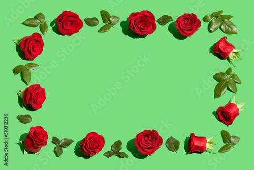 Creative flowers composition. Vintage frame made of red roses on green background. Minimal flat lay. Valentine's Day or love concept.
