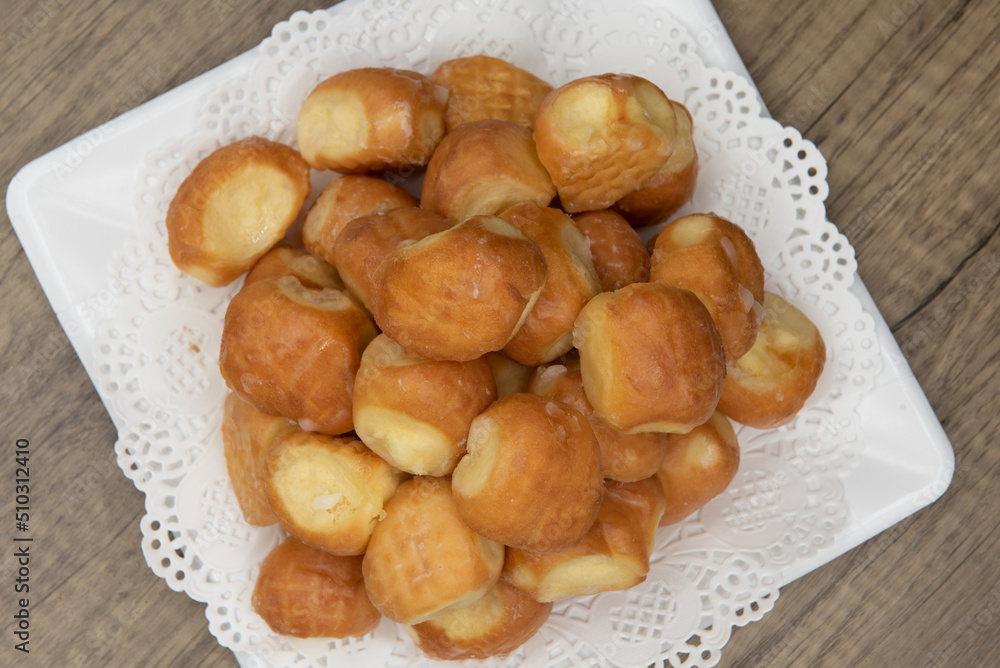 Overhead view of tempting fresh from the oven glazed donut holes from the bakery stacked on a plate Overhead view of tempting fresh from the oven glazed donut holes from the bakery stacked on a plate