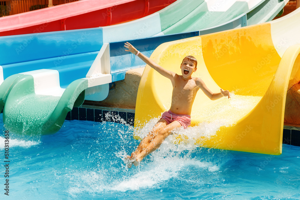  Boy having funin water park. A kid is slithering down the water slide and making splashes. 