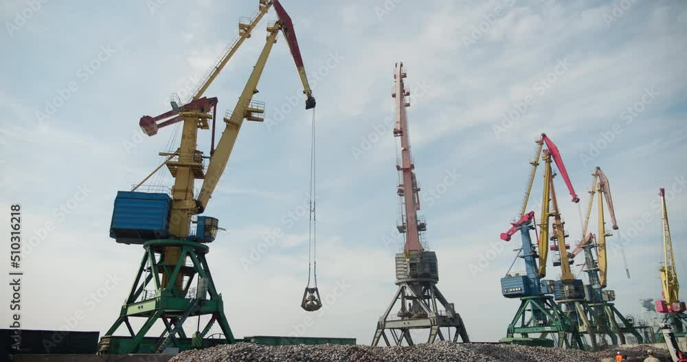 Operation of cargo cranes in the port. Unloading of cast iron. Business concept, logistics of transportation by sea. Commercial seaport Operation of cargo cranes in the port. Unloading of cast iron. Business concept, logistics of transportation by sea. Commercial seaport