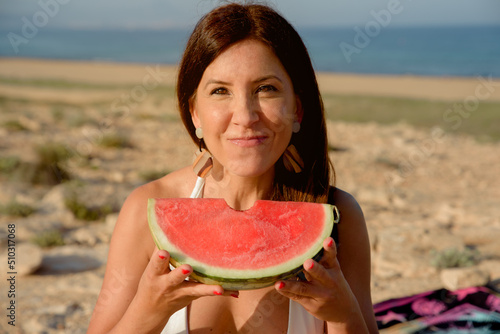 Woman enjoy eating a watermelon outdoors on the beach