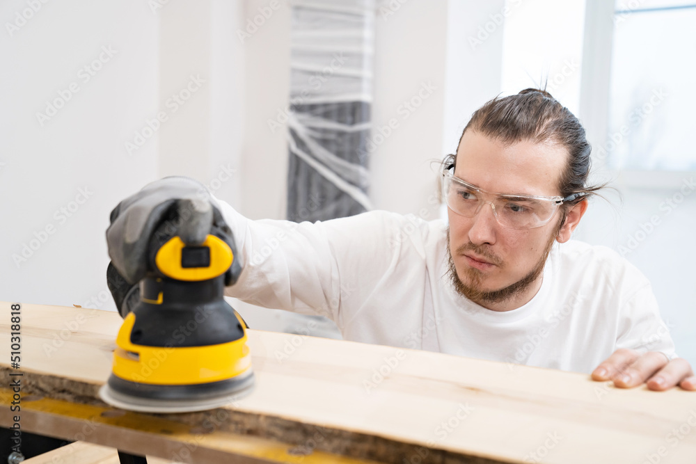 carpenter in protective gloves and glasses for working on wood grinding machine carpenter in protective gloves and glasses for working on wood grinding machine