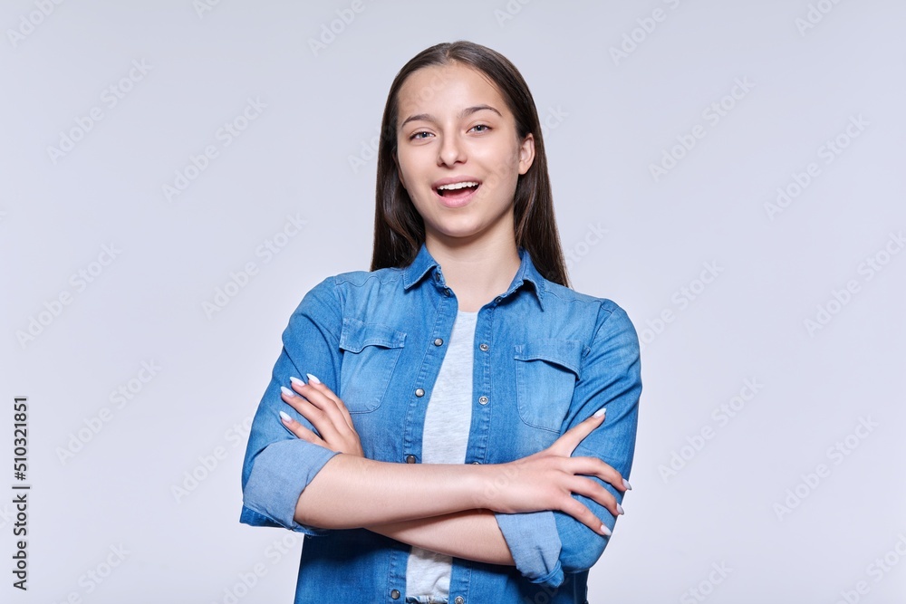 Portrait of smiling beautiful teenage girl looking at camera on light background