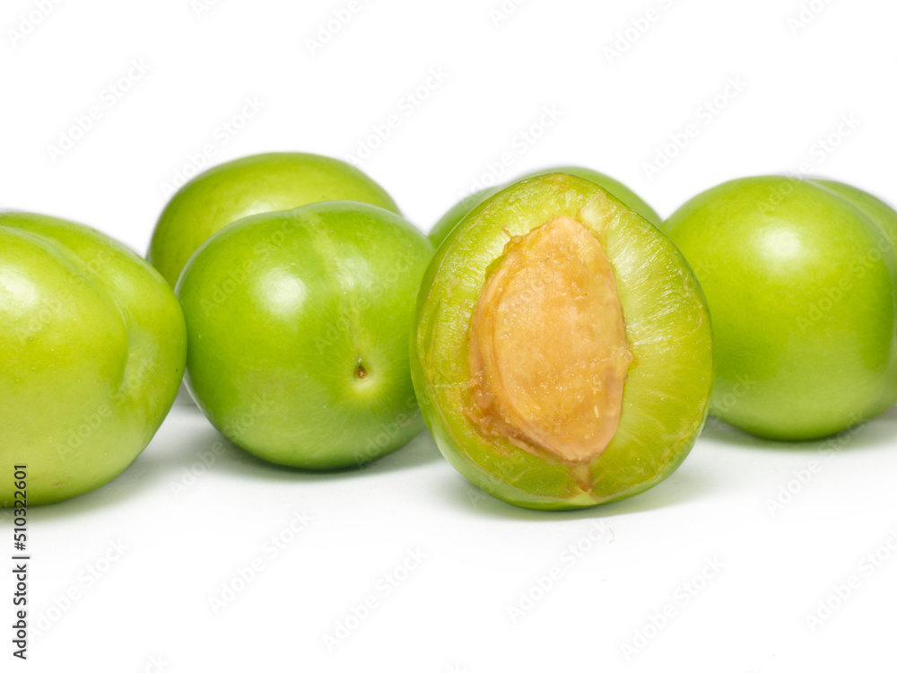 Green cherry plum on a white background. Fruit for making tkemali sauce. Diet food. Useful fruits. Juicy cut green plum Green cherry plum on a white background. Fruit for making tkemali sauce. Diet food. Useful fruits. Juicy cut green plum