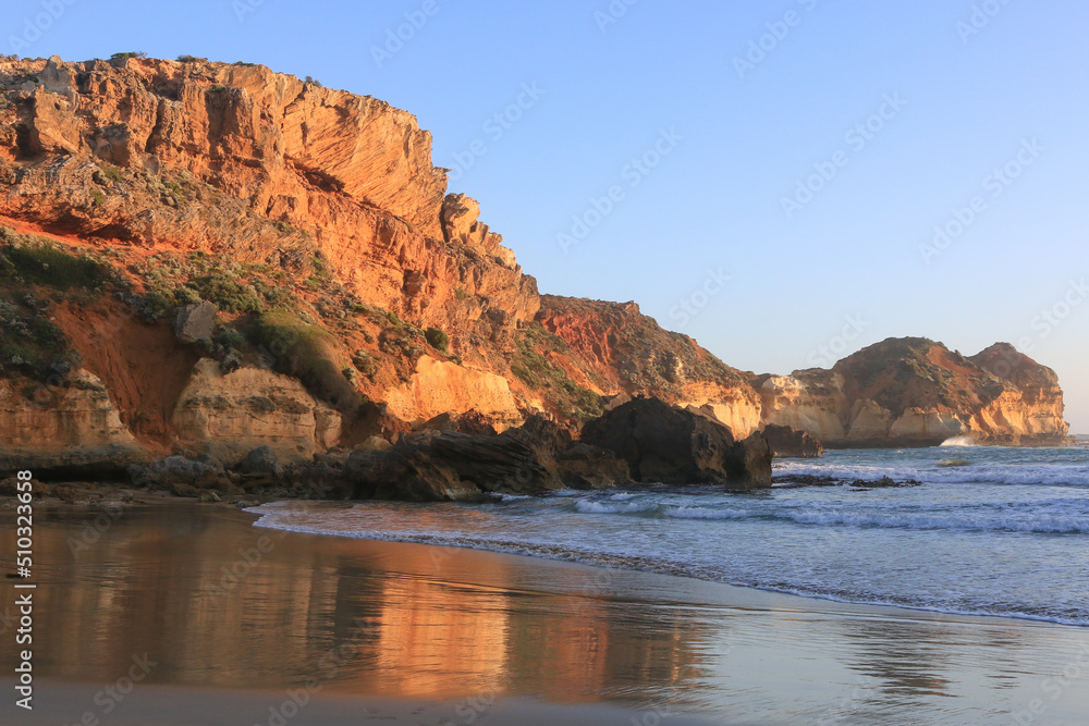 Great ocean road coast overlooking the Twelve Apostles Marine National Park - waves at sunset on the beach surrounded by big orange cliffs. Great ocean road coast overlooking the Twelve Apostles Marine National Park - waves at sunset on the beach surrounded by big orange cliffs.
