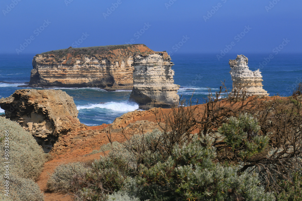 Great ocean road coast overlooking the Twelve Apostles Marine National Park - waves at sunset on the beach surrounded by big orange cliffs.