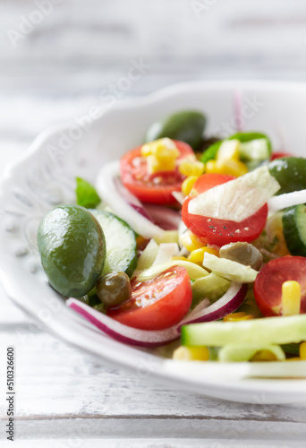 Simple Salad with Green Olives, Cucumber, Cherry Tomatoes and Capers. Bright wooden background. Close up. 