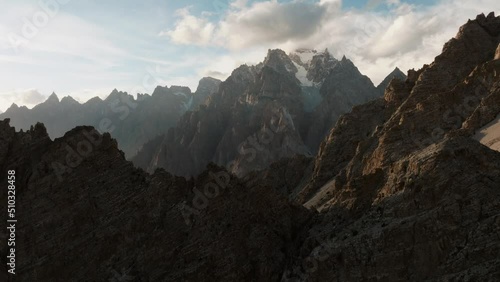 Aerial, drone moves forward slowly revealing amazing sharp mountain and then turns and reveals valley during sunset time,  shot with mavic 3 drone in Passu, Pakistan