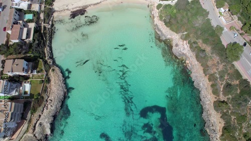 Flight above the crystal clear water to reveal a white sandy beach of Cala Marcal photo