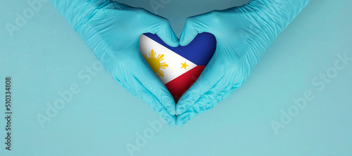 Doctors hands wearing blue surgical gloves making hear shape symbol with philippines flag photo