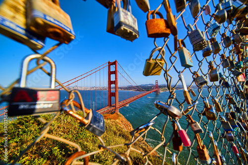 Photography San Francisco iconic Golden Gate Bridge through opening in fence covered in lock