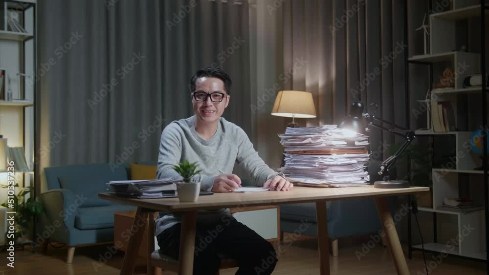 Asian Man Smiling To Camera While Working With Documents At Home
Asian Man Smiling To Camera While Working With Documents At Home