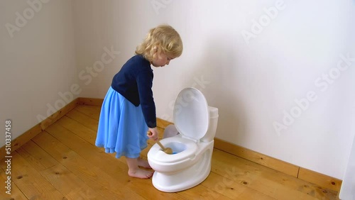 A child cleaning a potty toilet with detergent and a brush photo