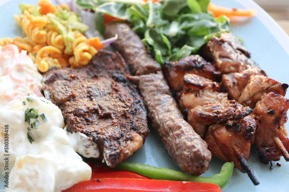 South African braai meat including lamb chops, boerewors sausage and chicken kebabs with potato salad, coleslaw and curry pasta salad 