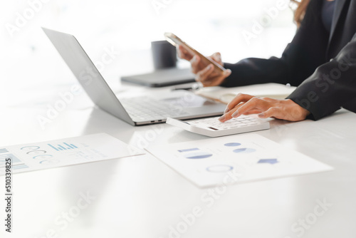 Business women using calculator at working with financial report.