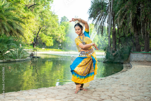 Fotografie Young Indian woman Odissi dancer doing classical dance form outdoor at nature park