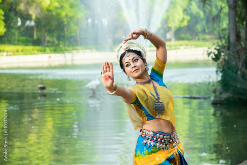 Indian woman Odissi dancer doing classical dance form outdoor at nature park. Orissi dance. art and culture of india.