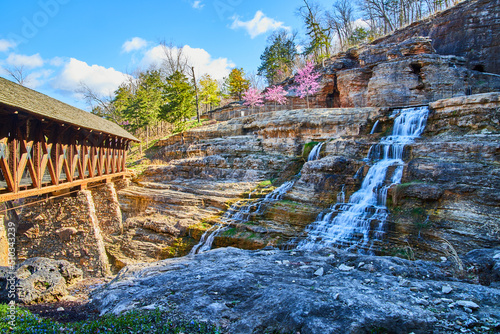 Stunning waterfalls cascading down into valley under wood bridge in early spring photo