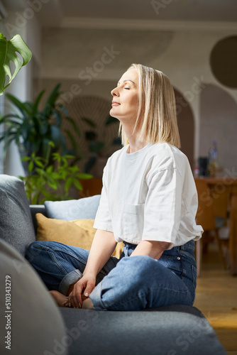 Adult woman sitting on the couch with closed eyes. Mindfulness concept photo