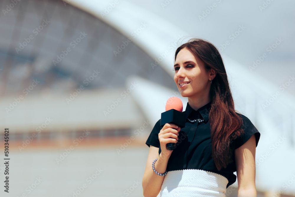 Happy Journalist Holding a Microphone Reporting Outdoors. Female reporter standing outside broadcasting live
