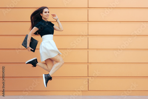 Happy Cheerful Businesswoman Jumping Holding a Portfolio Case. Carefree, energetic freelance working wearing fashionable outfit for business meeting
