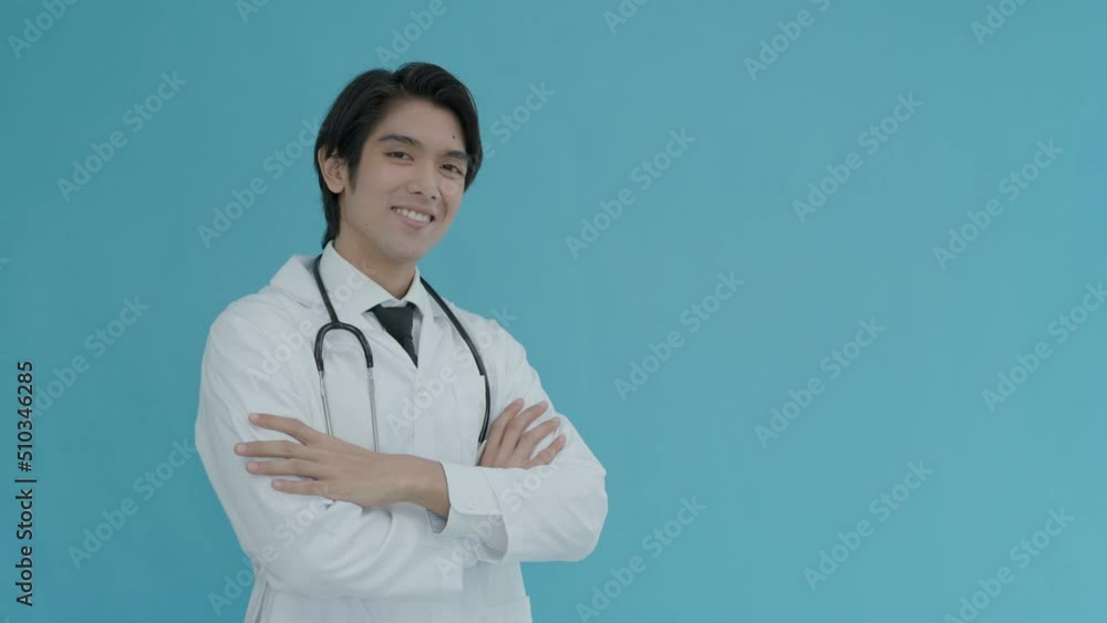 Asian doctor is hugging and smiling kindly. joyful doctor in white lab coat and stethoscope on his neck, having his arms crossed, looking at camera, isolated on background. Asian doctor is hugging and smiling kindly. joyful doctor in white lab coat and stethoscope on his neck, having his arms crossed, looking at camera, isolated on background.