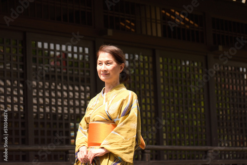 日本家屋の前で和服でたたずむシニア女性