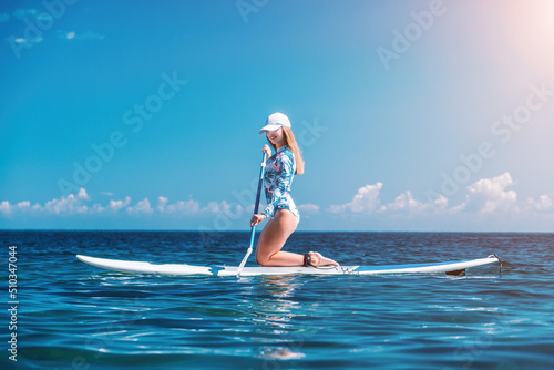 Healthy happy fit woman in bikini relaxing on a sup surfboard  floating on the clear turquoise sea water. Recreational Sports. Stand Up Paddle boarding. Summer fun  holidays travel. Active lifestyle