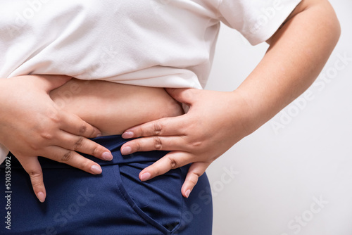 Close up shot at the tummy or waist belly of chubby women that show sign of overweight. On white background with copy space for text
