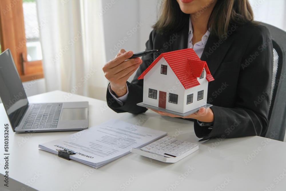Accountant, businessman, real estate agent, business woman handing model house to customers along with house interest calculation documents for customers to sign. Accountant, businessman, real estate agent, business woman handing model house to customers along with house interest calculation documents for customers to sign.