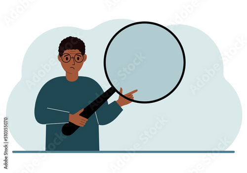 A man holds a large loupe or magnifying glass in his hands.