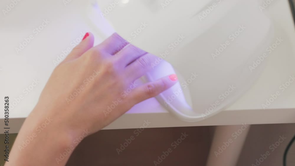 Master cared for woman's fingers and client insert hand into UV lamp for drying gel varnish. Close-up. Professional manicure in salon. Master cared for woman's fingers and client insert hand into UV lamp for drying gel varnish. Close-up. Professional manicure in salon.