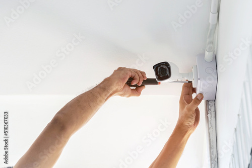Technicians using a screwdriver to install the CCTV cameras on the walls of the house for security purposes.