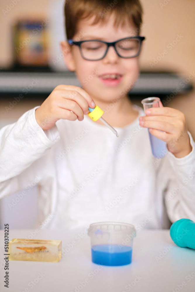 boy is engaged in scientific research. A child with a test tube and a pipette in his hands. The boy makes an experiment at home. boy is engaged in scientific research. A child with a test tube and a pipette in his hands. The boy makes an experiment at home.