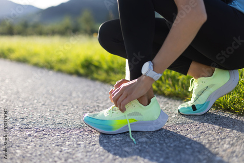 Close-up of sportive young woman tying her shoes