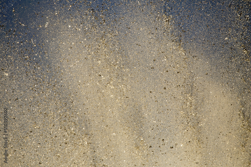 Bright splashes of the water fountain against the blue sky. Abstract color composition in sunshine backlight. Bright splashes of the water fountain against the blue sky. Abstract color composition in sunshine backlight.