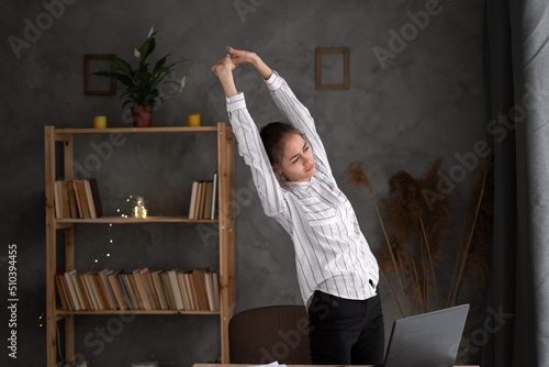 unhappy young businesswoman suffering from backache, problem after long hours sedentary work, frustrated upset woman employee worker standing in office feeling back pain photo