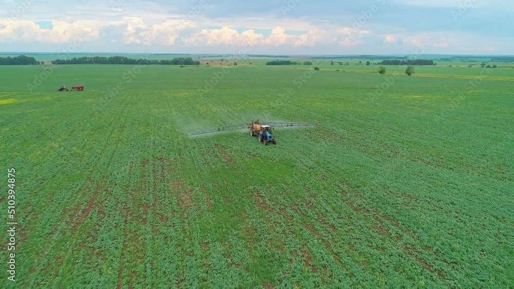 Aerial panoramic view of a tractor machine spraying the field with pesticides. Farm machinery spraying the field against pests. Aerial panoramic view of a tractor machine spraying the field with pesticides. Farm machinery spraying the field against pests.