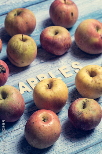 Many yellow and red apples fruit with apples word written on wooden letters on a blue background