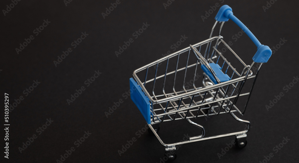Mini blue supermarket trolley on black background. Shopping concept