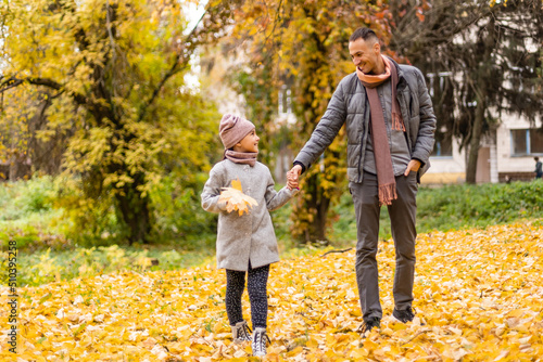 Happy father and daughter in autumn park on yellow leaves