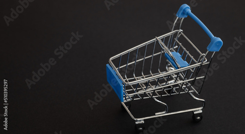Mini blue supermarket trolley on black background. Shopping concept