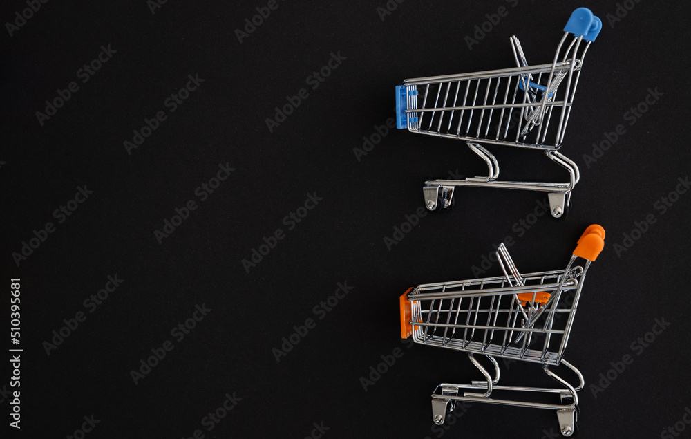 Mini color supermarket trolleys on black background. Shopping concept