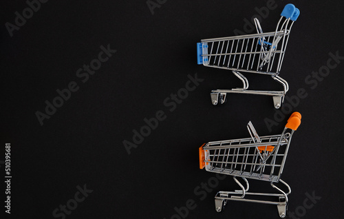 Mini color supermarket trolleys on black background. Shopping concept