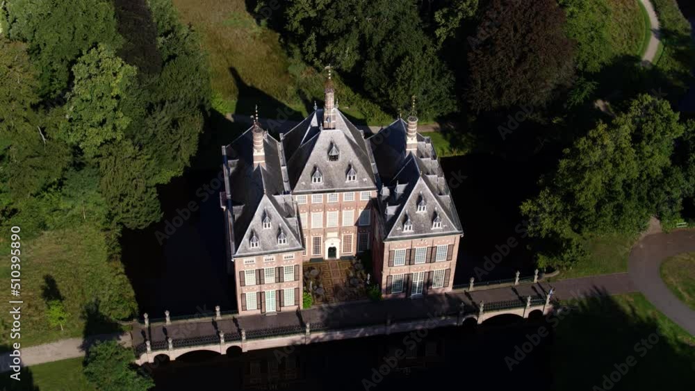 Panning drone shot of the lavish Duivenvoorde Castle, one of the oldest castles in South Holland, surrounded by lush green trees. Panning drone shot of the lavish Duivenvoorde Castle, one of the oldest castles in South Holland, surrounded by lush green trees.