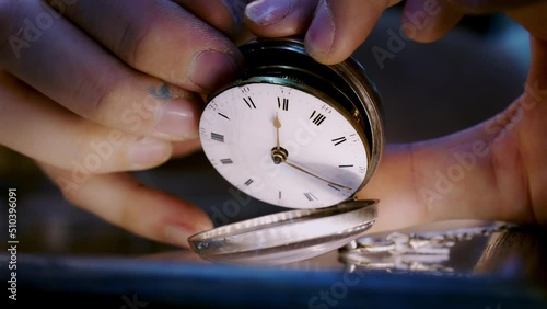 Hand gently pulls up Anitque pocket watch. photo