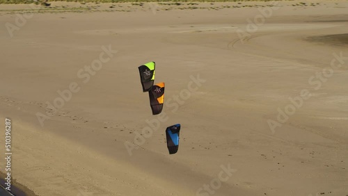Drone orbit three colorful wind kites lined up together in air at dutch beach  photo