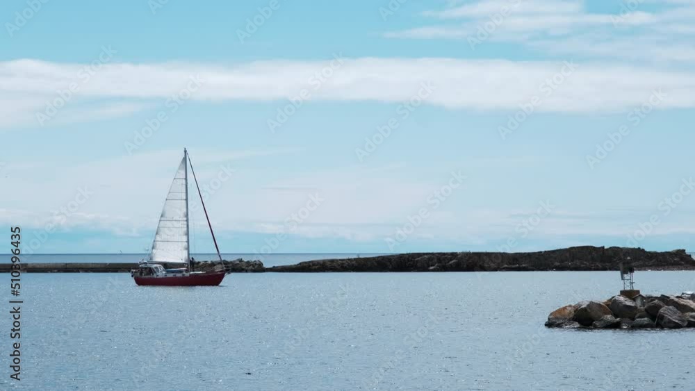 Sailboat on peaceful water in harbor against brilliant blue sky Sailboat on peaceful water in harbor against brilliant blue sky